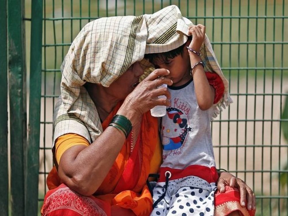 A woman offers water to her granddaughter as she covers her and herself to protect from sun stroke on a hot summer day in New Delhi, India, May 23, 2018. REUTERS/Adnan Abidi